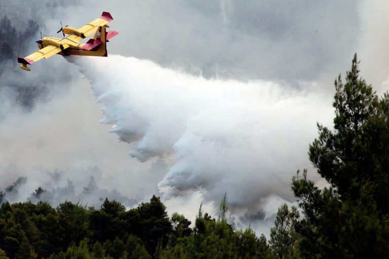 A,Plane,Drops,Water,During,A,Forest,Fire,On,Ouranoupoli,